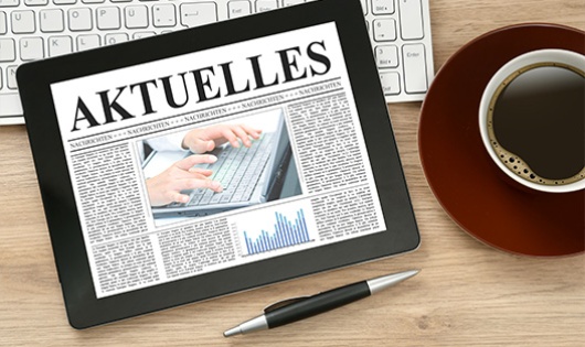 Tablet mit Schriftzug Aktuelles und Kaffeetasse